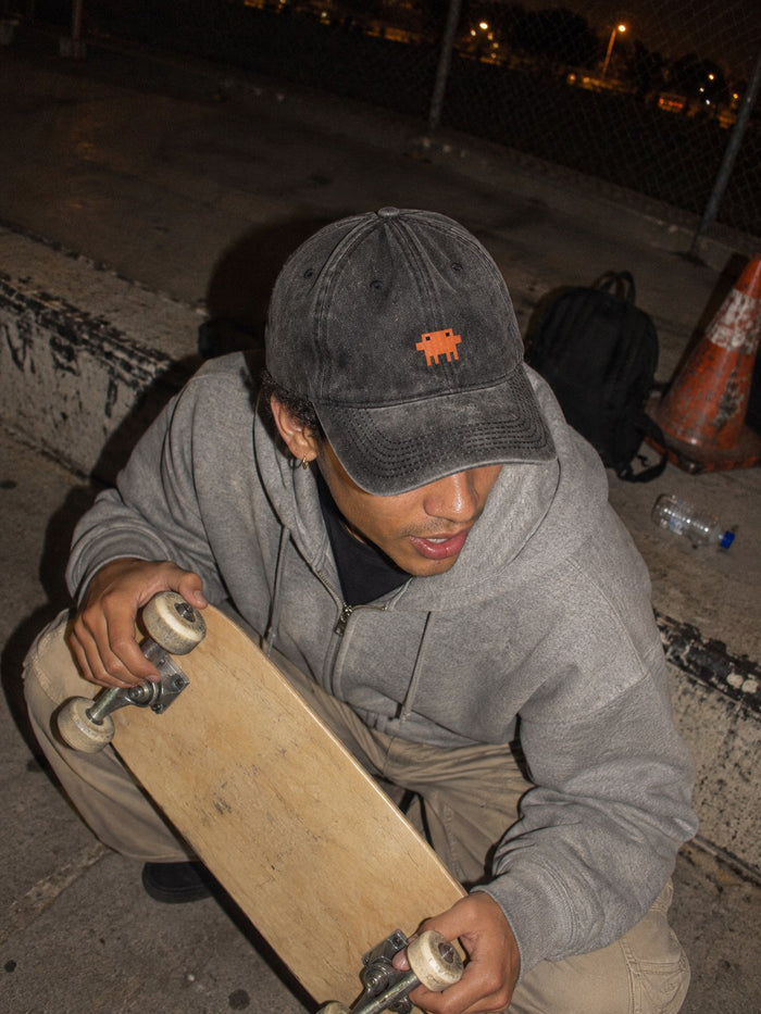 Rapaz numa pista de skate à noite usando o boné Claude Code preto